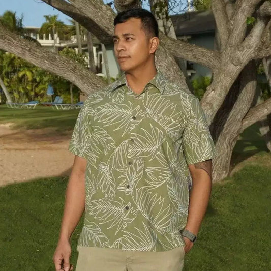 A man modeling a green aloha Hawaiian button-down shirt with a palm leaf pattern design. Made by Phin Hawaii.