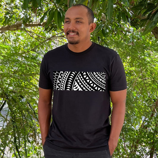 A man is modeling a black T-shirt with a white Polynesian Tribal design. This unisex shirt was created by Phin Hawaii and made in Hawaii. 