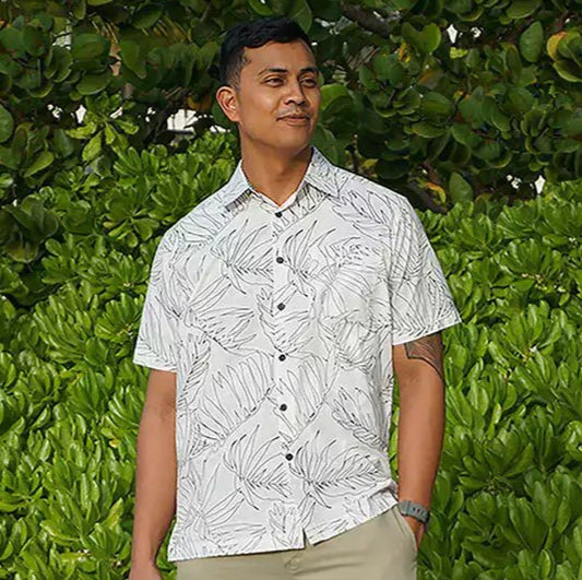 A man modeling a white aloha Hawaiian button-down shirt with a palm leaf pattern design. Made by Phin Hawaii.