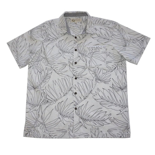 A white aloha Hawaiian button-down shirt with a palm leaf pattern is shown on a flat surface. It was made by Phin Hawaii.